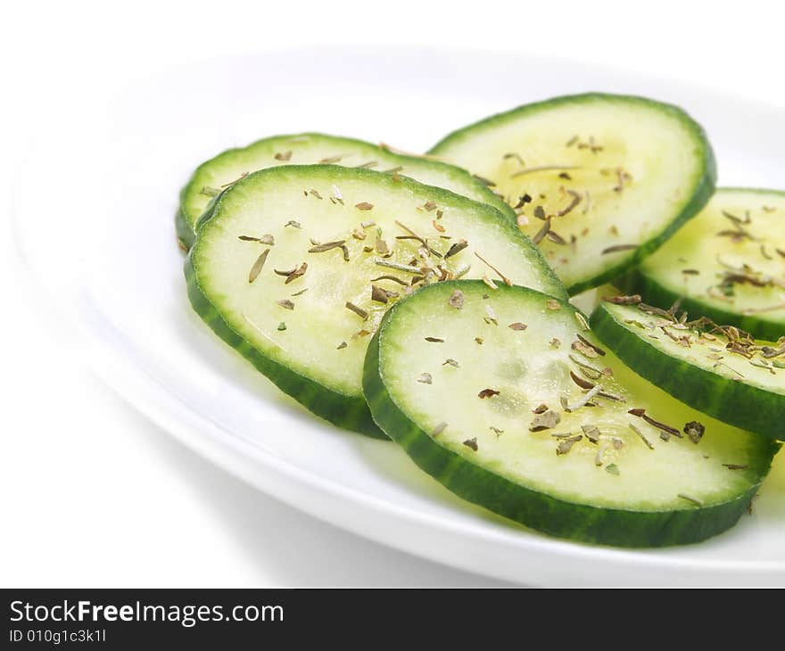 Fresh seasoned cucumber slices on a white plate