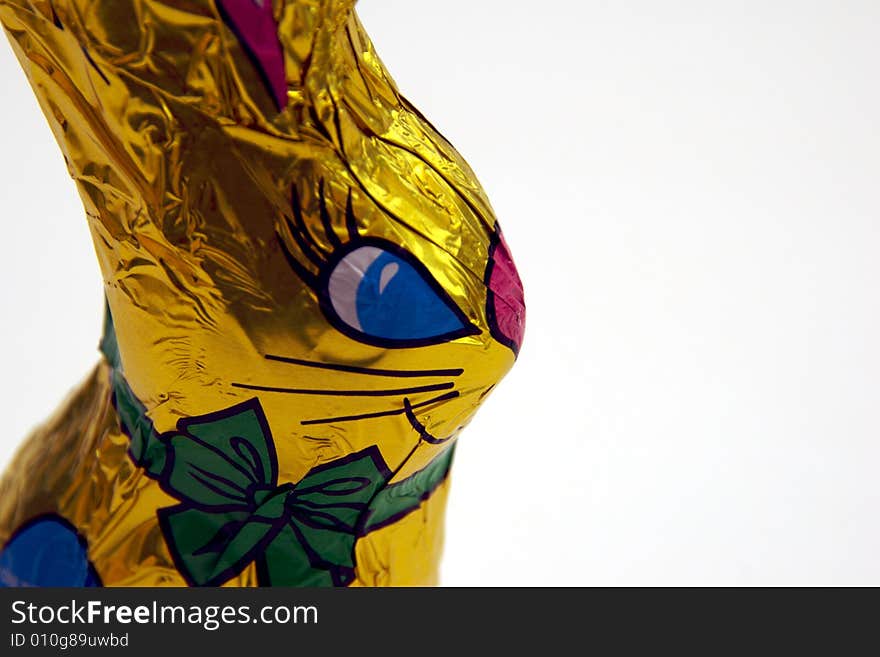 A golden-wrapped chocolate easter bunny on a white background.