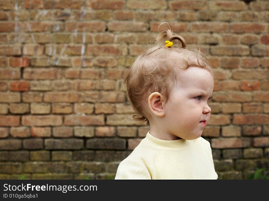 An image of baby near a yellow brick wall. An image of baby near a yellow brick wall