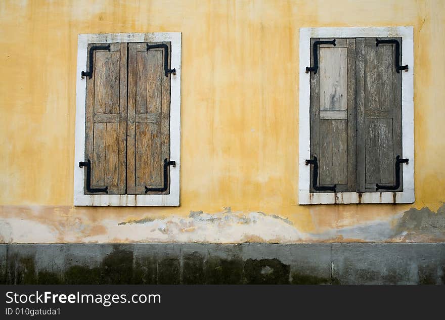 An image of wooden windows closed on yellow wall