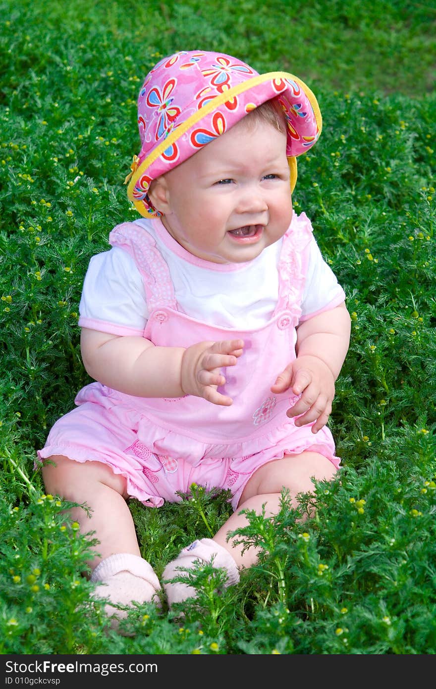 Small baby on green grass with chamomile flowers