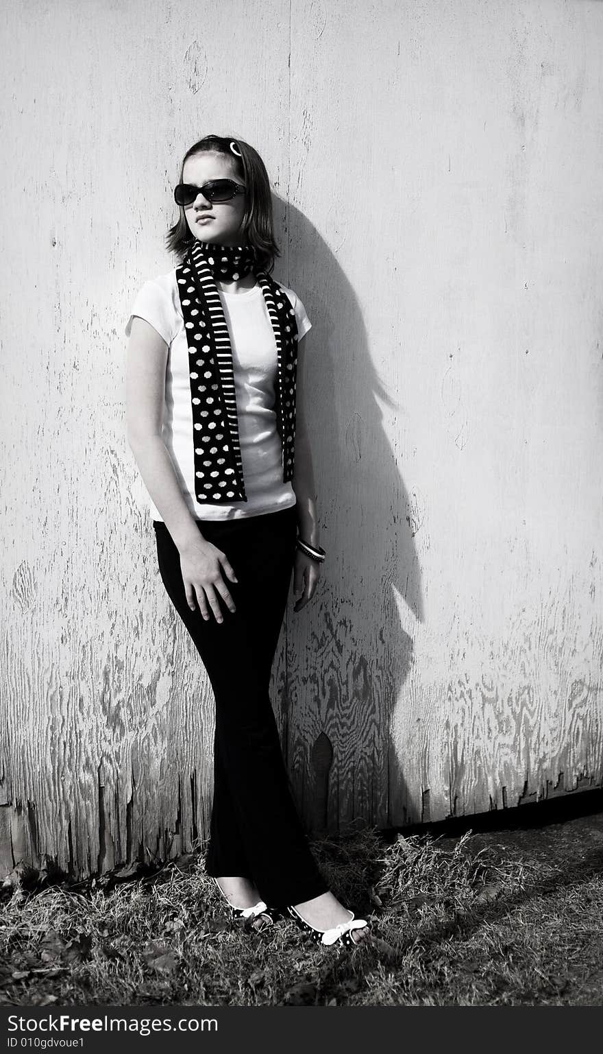 Attractive preteen girl standing against a weather wall.  Bright sunlight with shadows included for effect. Attractive preteen girl standing against a weather wall.  Bright sunlight with shadows included for effect.