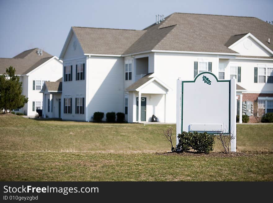 A blank sign in front of modern multi-housing units. A blank sign in front of modern multi-housing units.