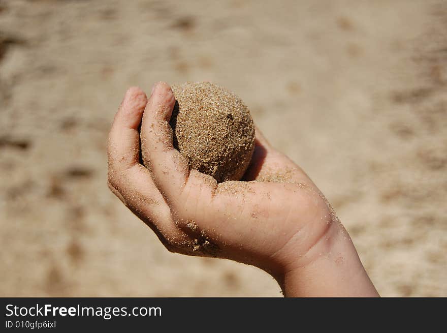 Small Child's hand holding wet sand ball