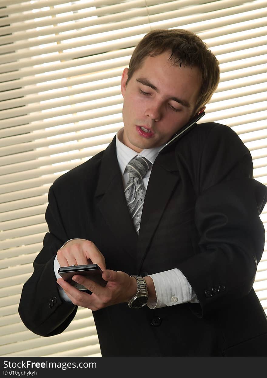 Businessman in office with calculator talking phone. Businessman in office with calculator talking phone