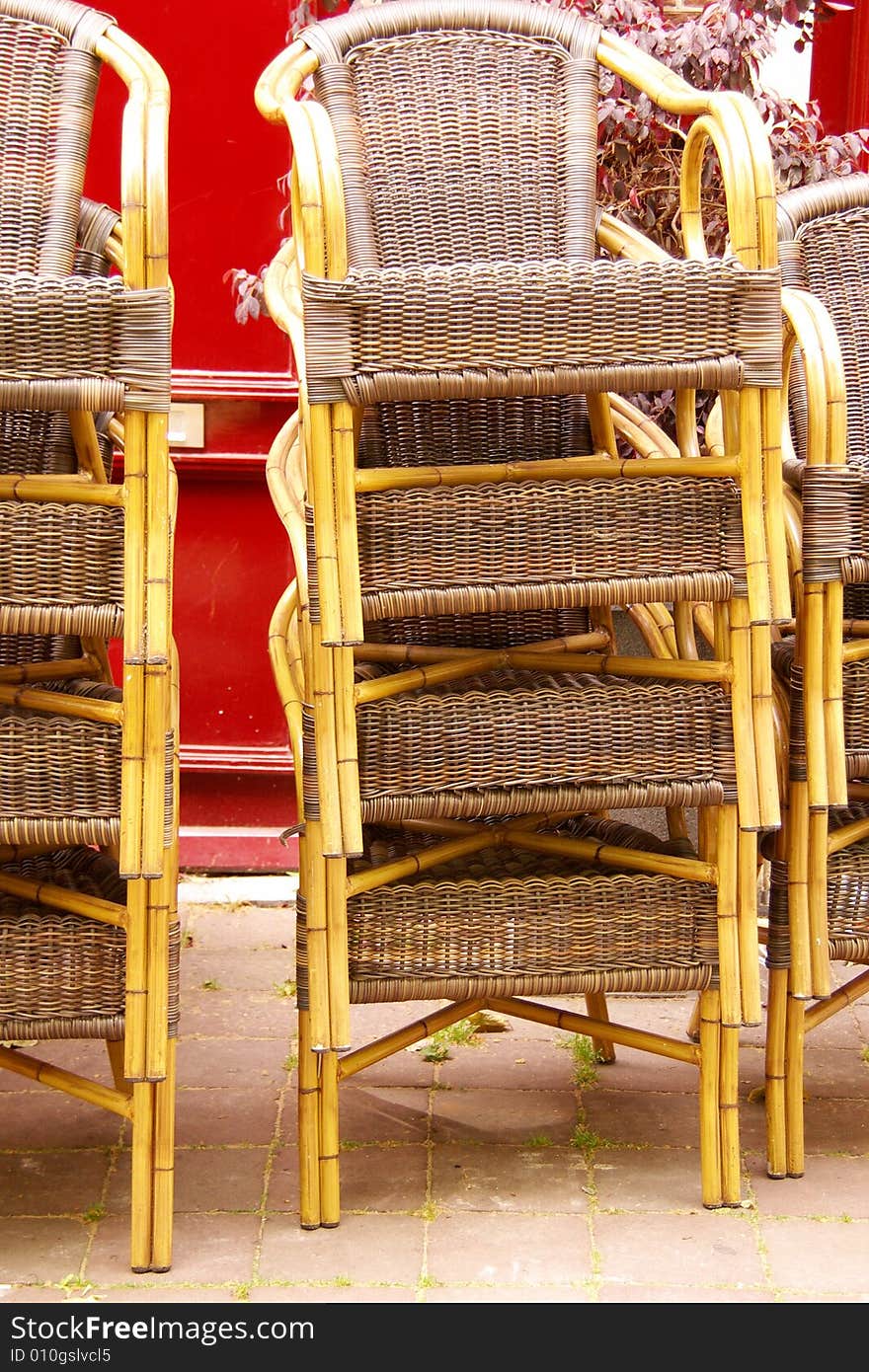 Stored chairs at a terrace in ftont of a red door