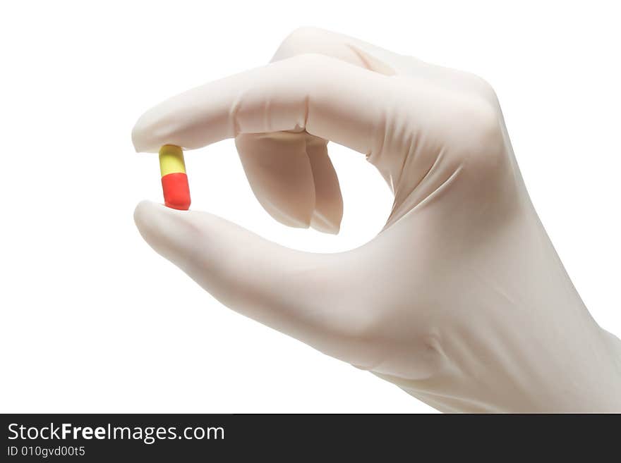 Red-and-yellow pill in nurse's hand,isolated, on white background. Red-and-yellow pill in nurse's hand,isolated, on white background