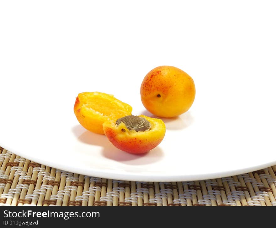 Ripe apricots and black currant on a white plate