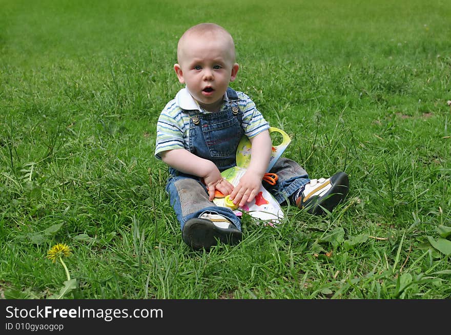 The kid playing on a grass in park. The kid playing on a grass in park