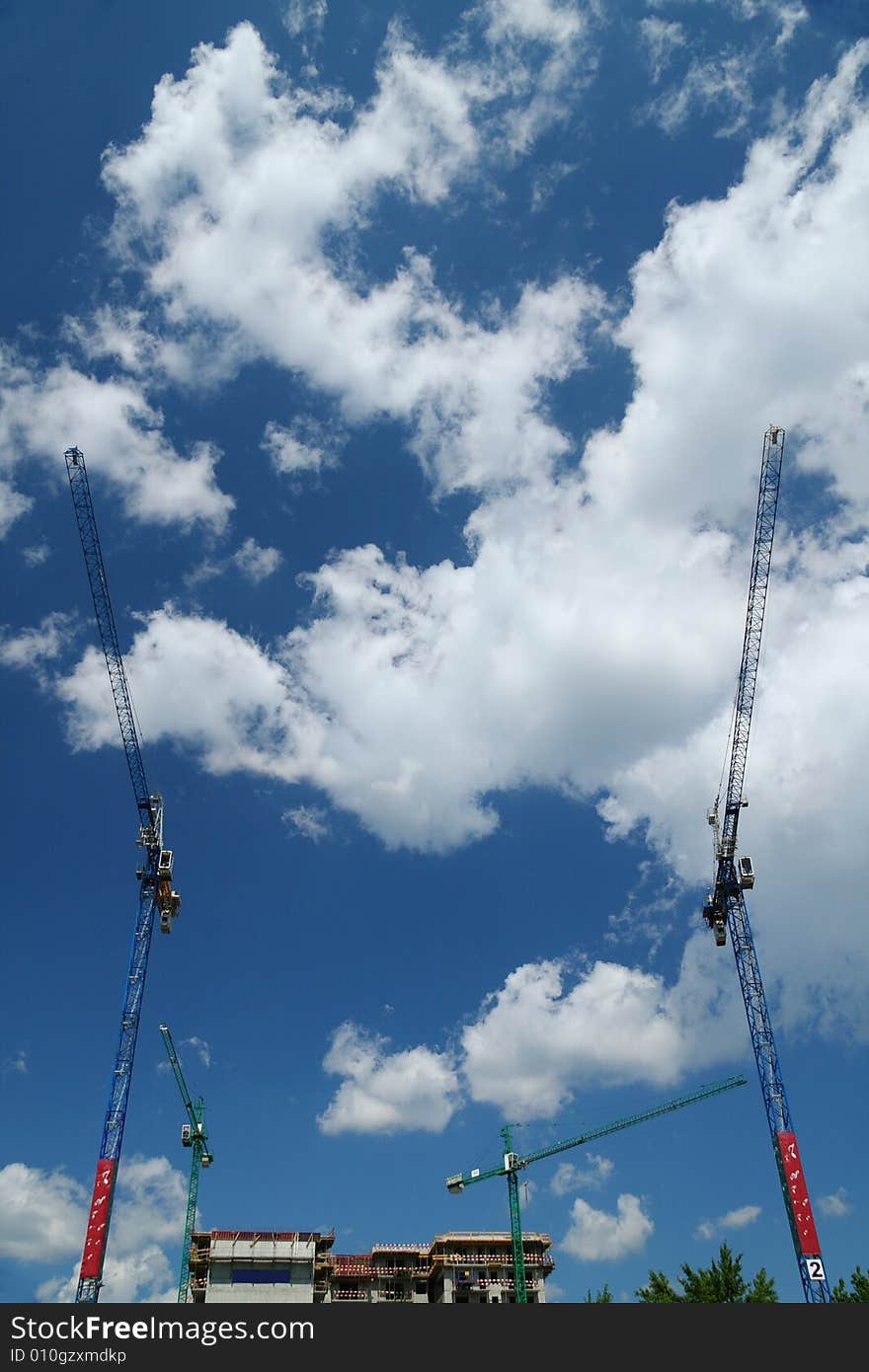 Construction cranes against nice clouds on a sky. Wide angle shot.