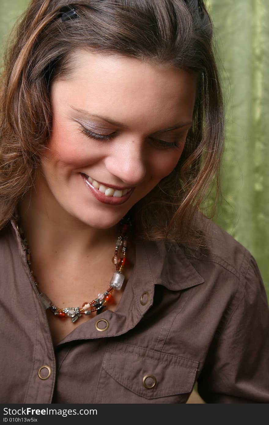 Beautiful brunette female wearing a brown shirt against a green background. Beautiful brunette female wearing a brown shirt against a green background