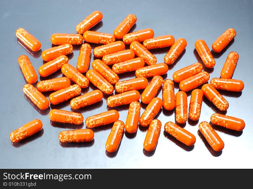 Drugs in orange capsules on grey background. Drugs in orange capsules on grey background