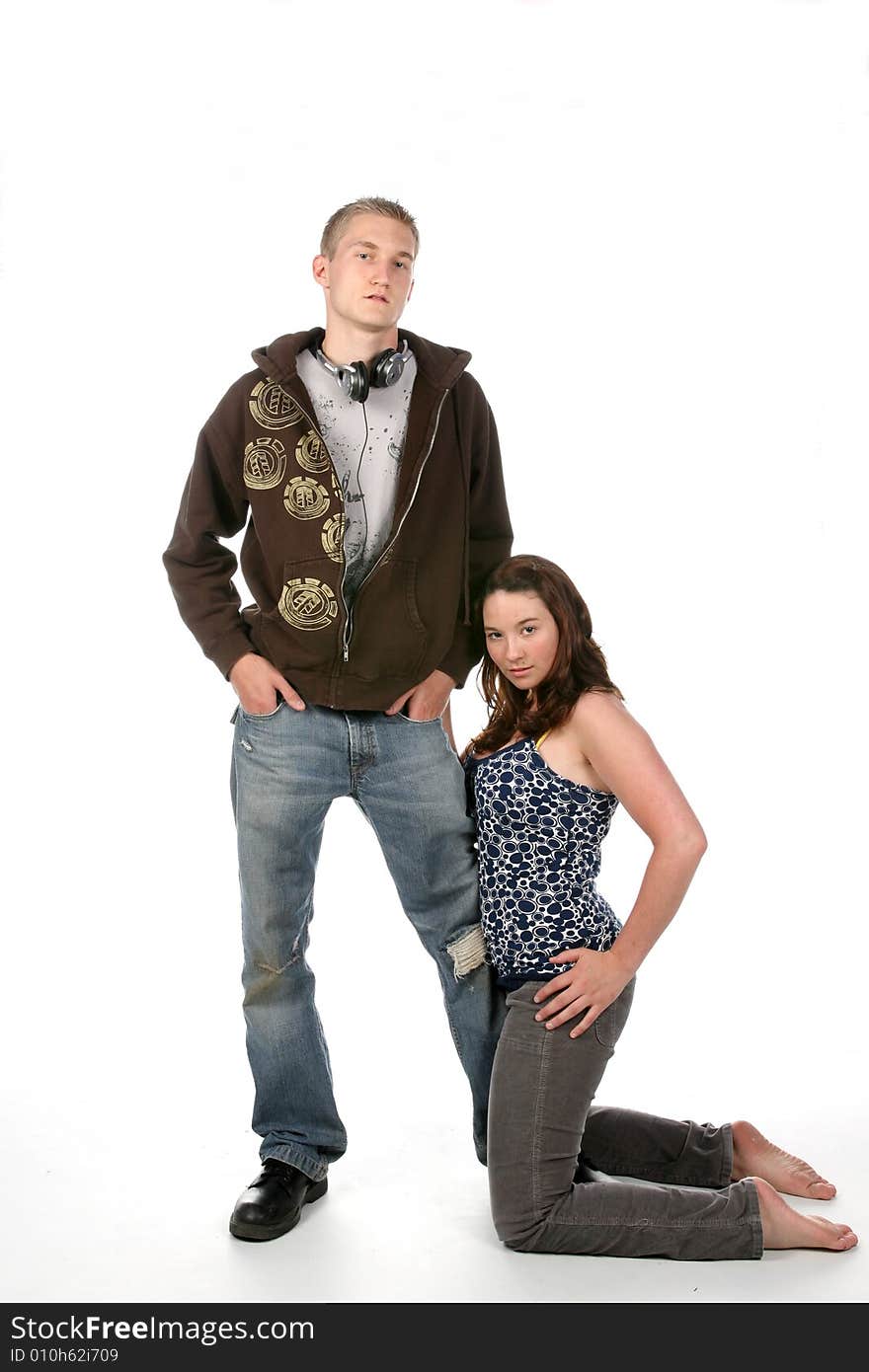 Grunge style man standing while girlfriend kneels next to him. Grunge style man standing while girlfriend kneels next to him