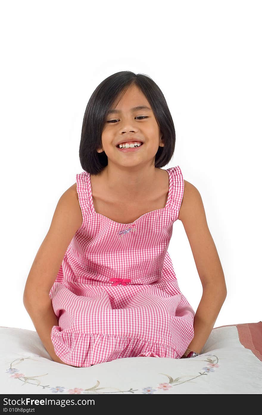 Young pretty Eurasian Chinese girl in pink dress seated on floor smiling. Young pretty Eurasian Chinese girl in pink dress seated on floor smiling