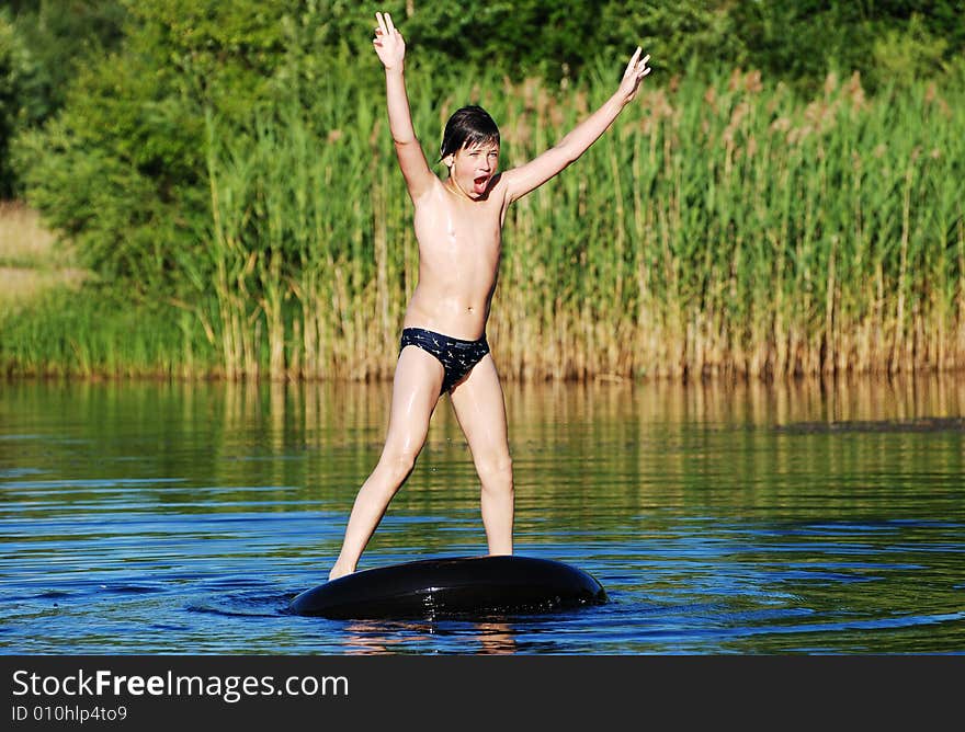 The boy finally stood up on a floating tube in a small lake. The boy finally stood up on a floating tube in a small lake.