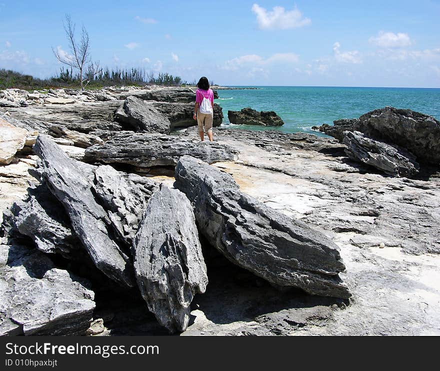 The girl walking along rocky hostile beach in Freeport on Grand Bahama Island, The Bahamas. The girl walking along rocky hostile beach in Freeport on Grand Bahama Island, The Bahamas.