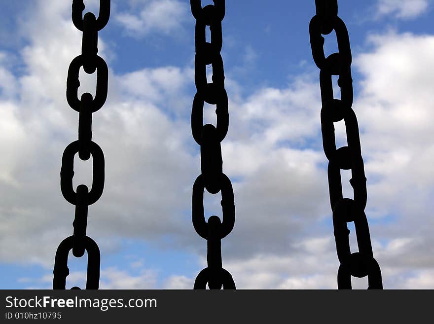 Three black chain hang down on sky background