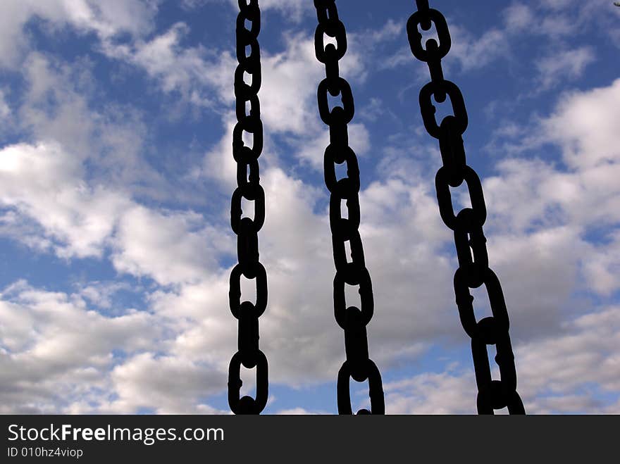 Three black chain hang down on sky background