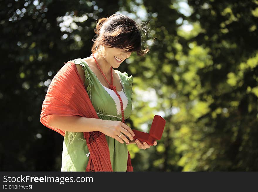 Young happy woman smiling outdoors with a jewelry box in her hands. Young happy woman smiling outdoors with a jewelry box in her hands