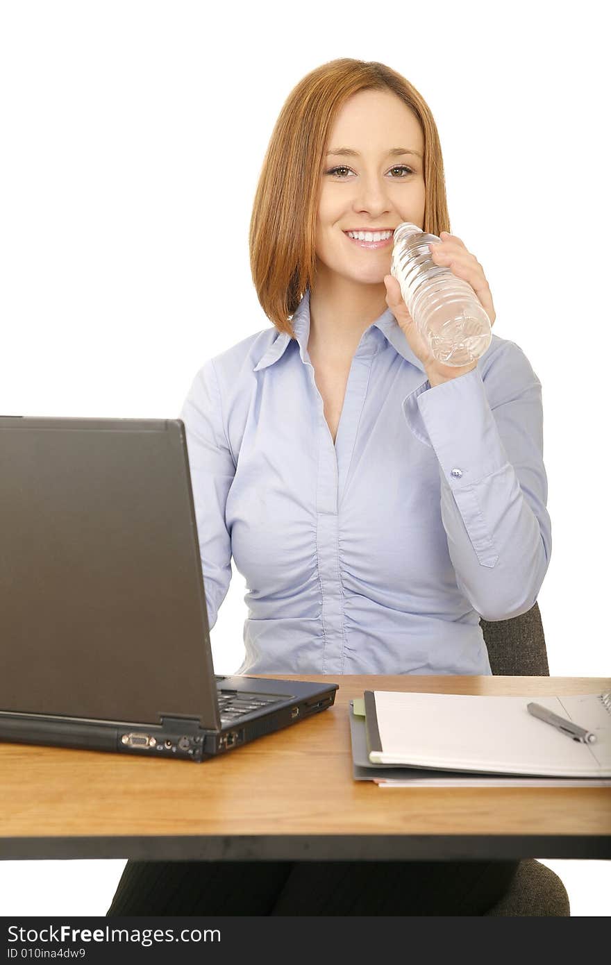 Young caucasian woman in casual dress working on her desk and drinking bottle water. Young caucasian woman in casual dress working on her desk and drinking bottle water