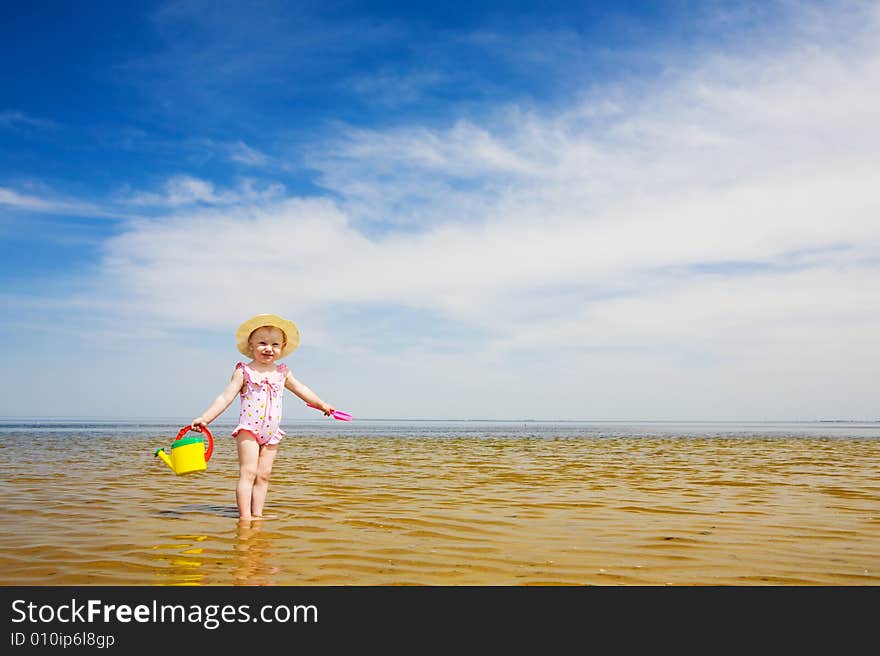 Small girl with watering-pot on the seashore. Small girl with watering-pot on the seashore