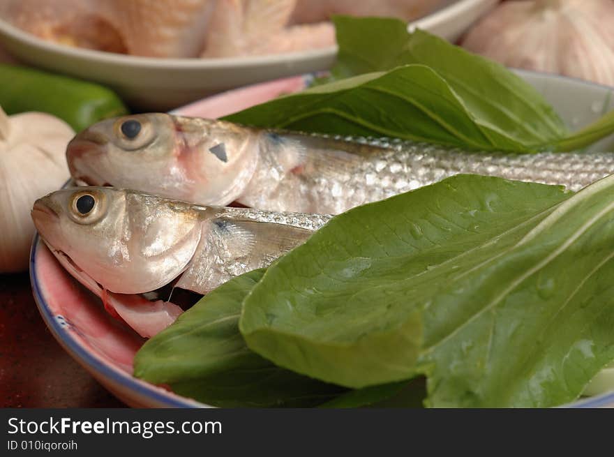 Two fishes and green vegetable in the dish, ready for cooking. Two fishes and green vegetable in the dish, ready for cooking.