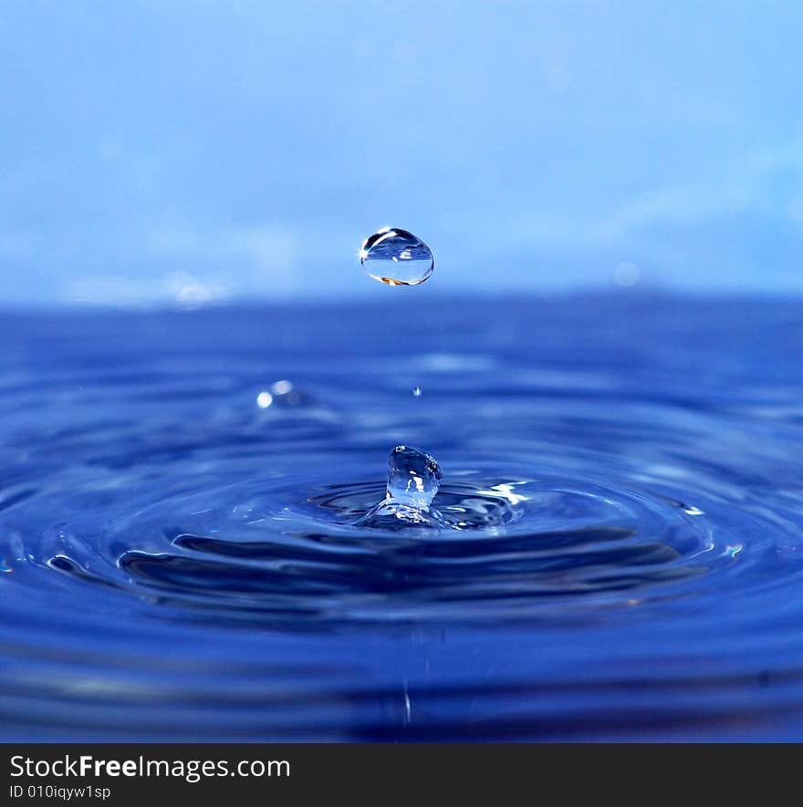 The round transparent drop of water falls downward. The round transparent drop of water falls downward