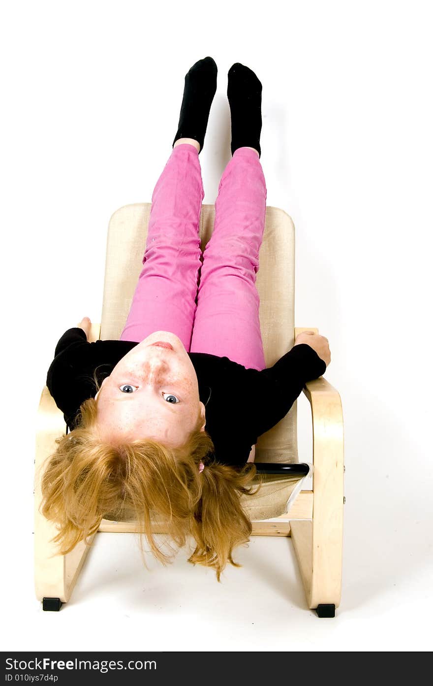 Little girl is hanging upside down on a chair