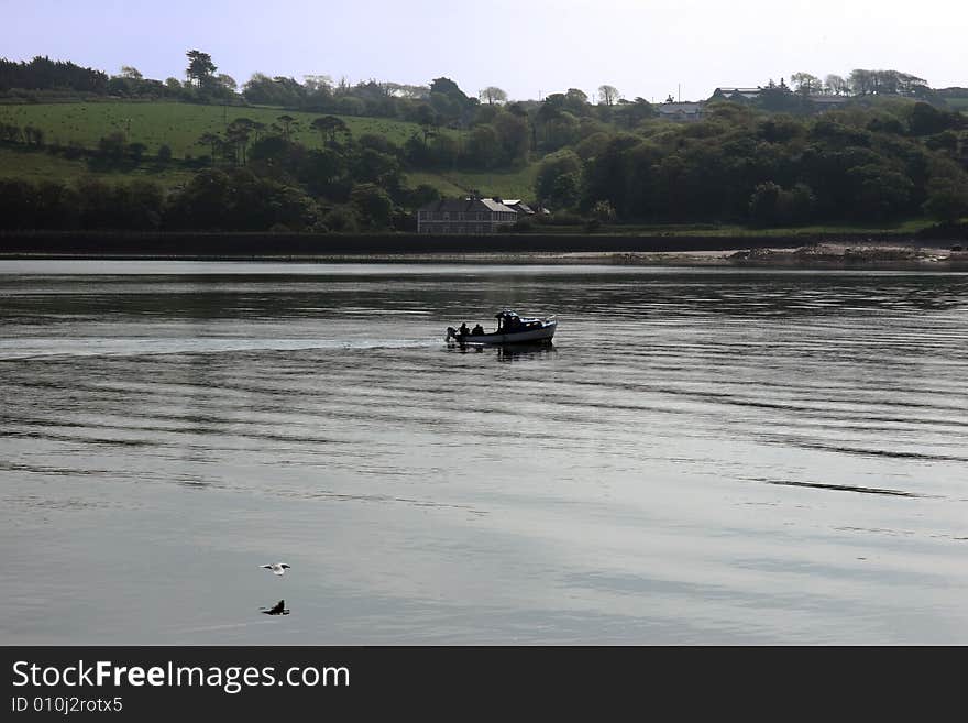 People fishing from a boat on the river blackwater in ireland with a seagull flying by. People fishing from a boat on the river blackwater in ireland with a seagull flying by