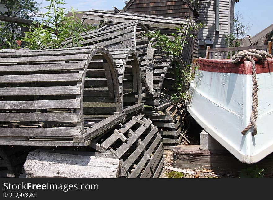 A stack of wooden lobster traps next to a rowboat on the dock. A stack of wooden lobster traps next to a rowboat on the dock