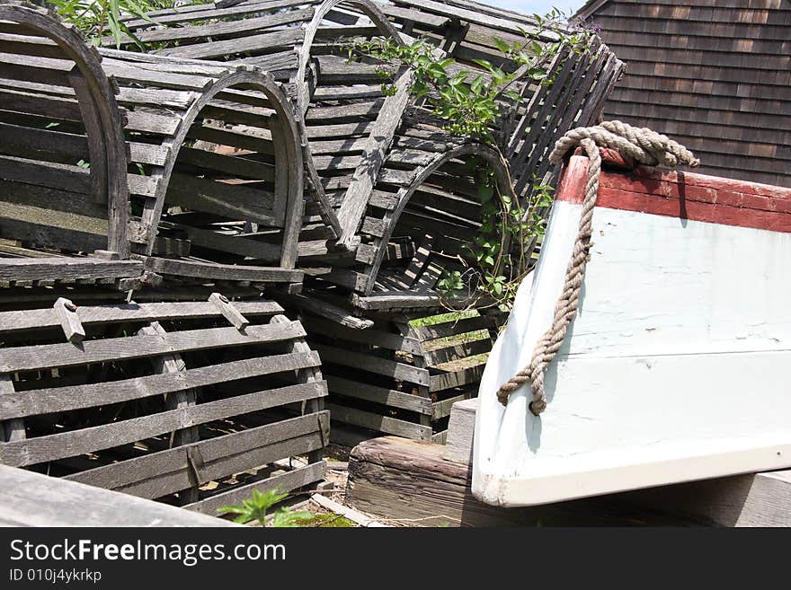 A stack of wooden lobster traps next to a rowboat on the dock. A stack of wooden lobster traps next to a rowboat on the dock