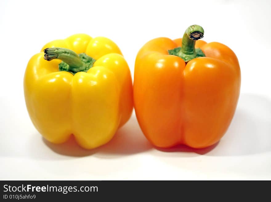 Two bell peppers, one yellow, another orange, isolated on a white background. Two bell peppers, one yellow, another orange, isolated on a white background.