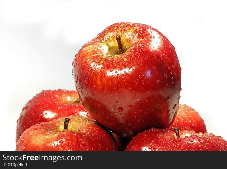 Red apple on top of others, isolated on a white background, with drops of water. Red apple on top of others, isolated on a white background, with drops of water.