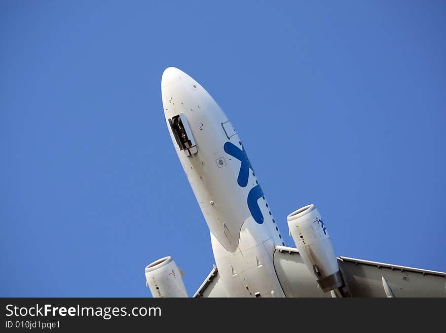 Half view below of a commercial plane arriving at the airport, with a blue sky. Half view below of a commercial plane arriving at the airport, with a blue sky.