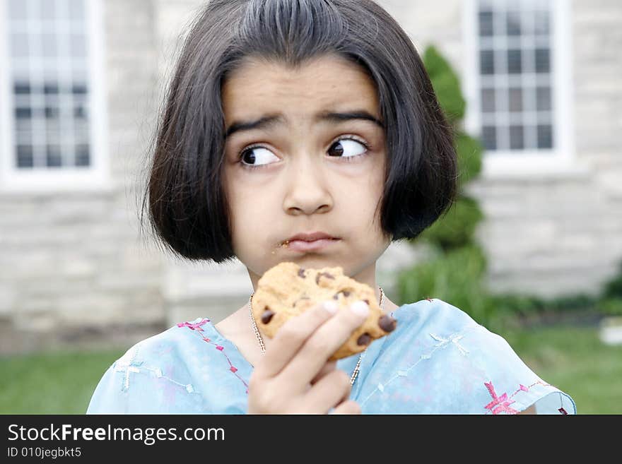 East indian little girl eating a chocolate chip cookie. East indian little girl eating a chocolate chip cookie