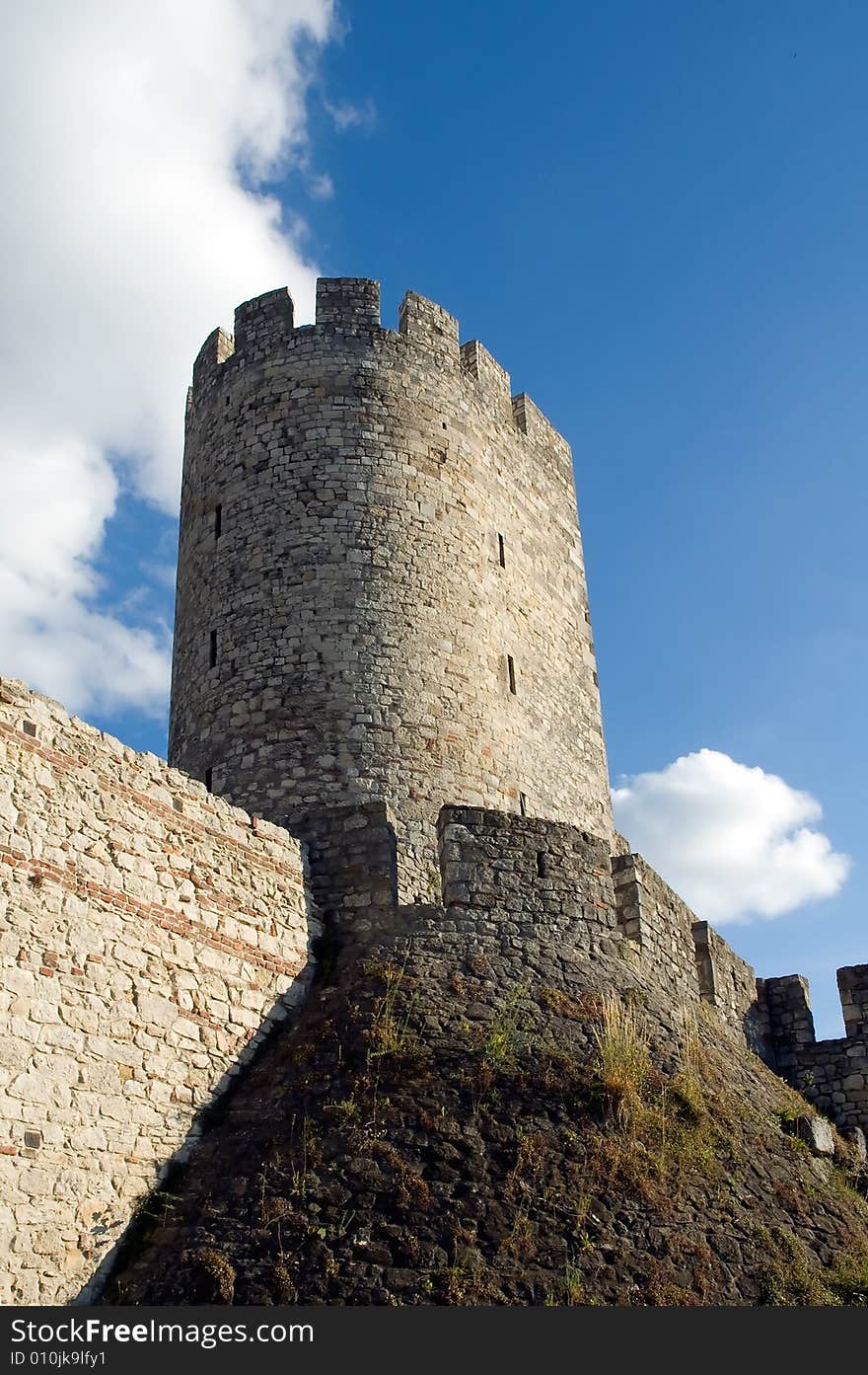 Ancient medieval fortress tower on a hill with a sky background