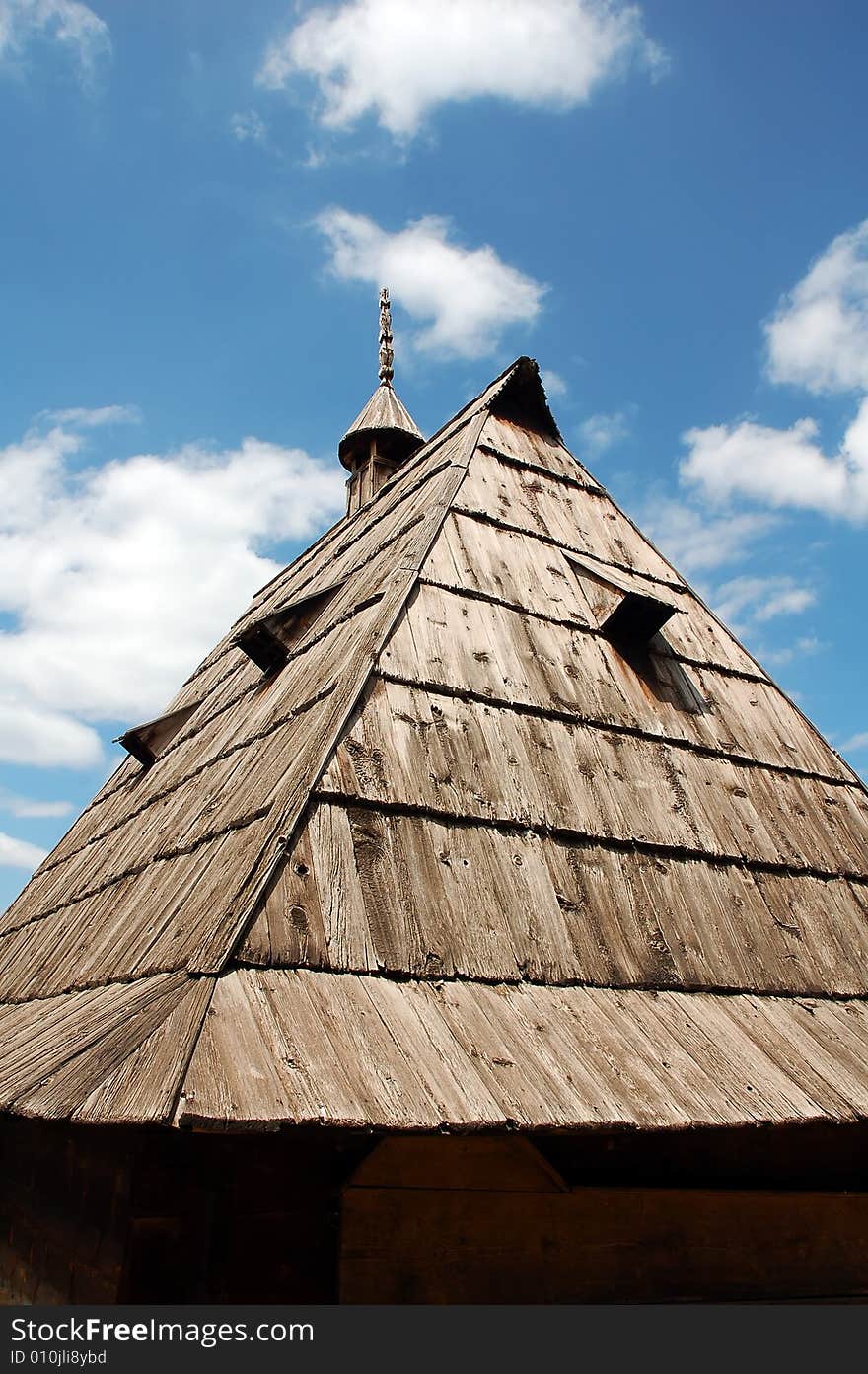 An old wooden roof on a primitive country house with a wooden with a decorative chimney. An old wooden roof on a primitive country house with a wooden with a decorative chimney