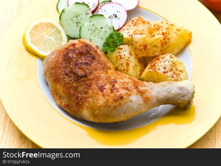 Fried chicken with fried potatoes, and cucumber,tomato,radish.