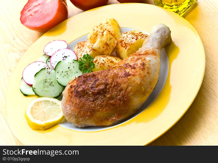 Fried chicken with fried potatoes, and cucumber,tomato,radish.