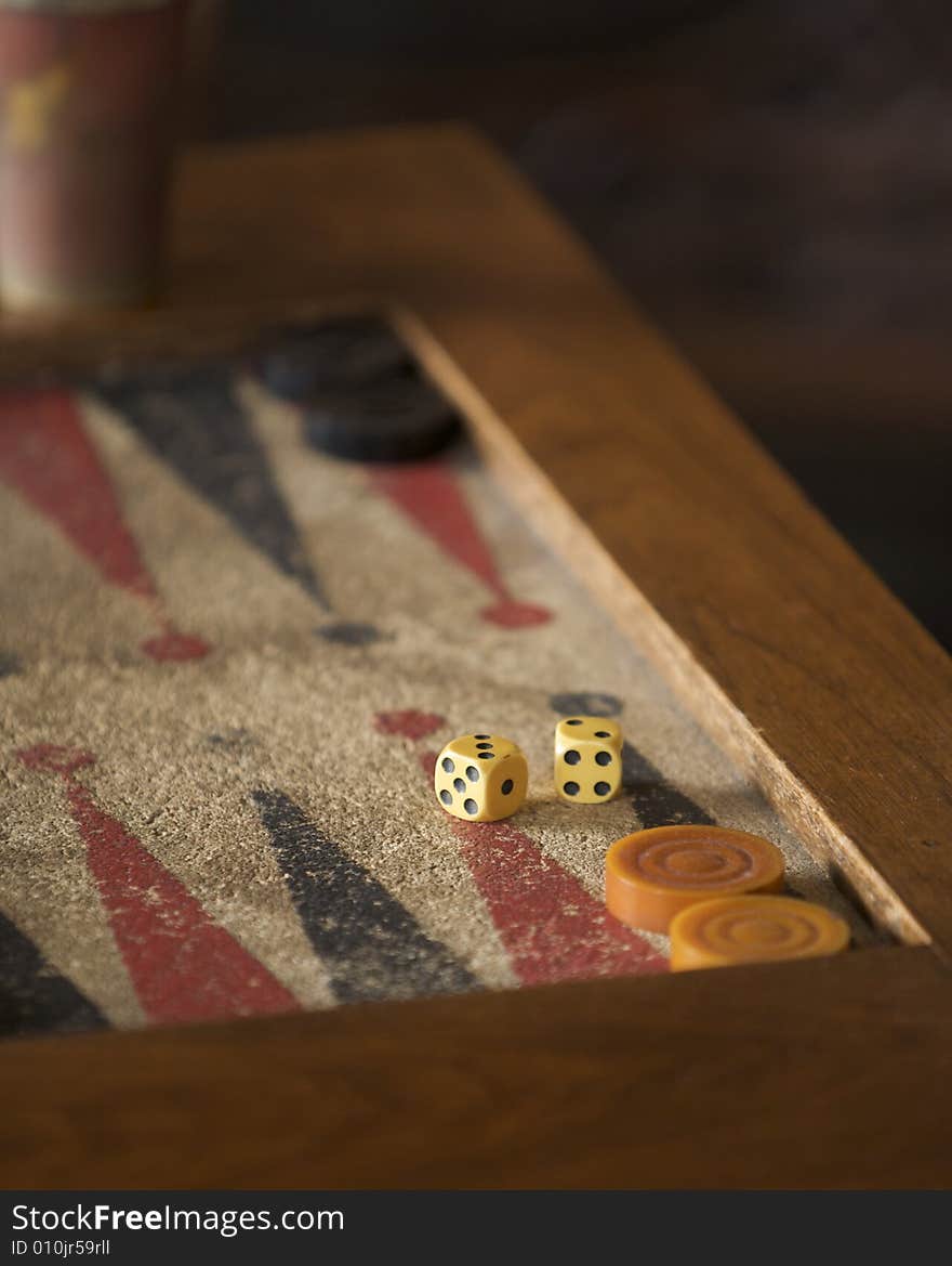 Ancient traditional backgammon board and ivory dice. The board is shown in partial view and is worn and faded by light. Ancient traditional backgammon board and ivory dice. The board is shown in partial view and is worn and faded by light