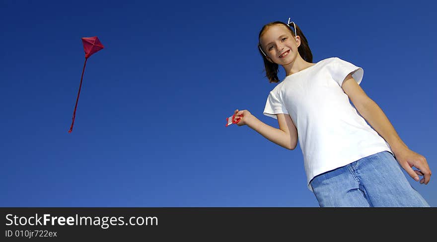 Girl flying a kite in a park with blue sky