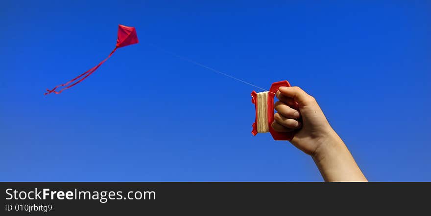 Girl flying a kite in a park with blue sky