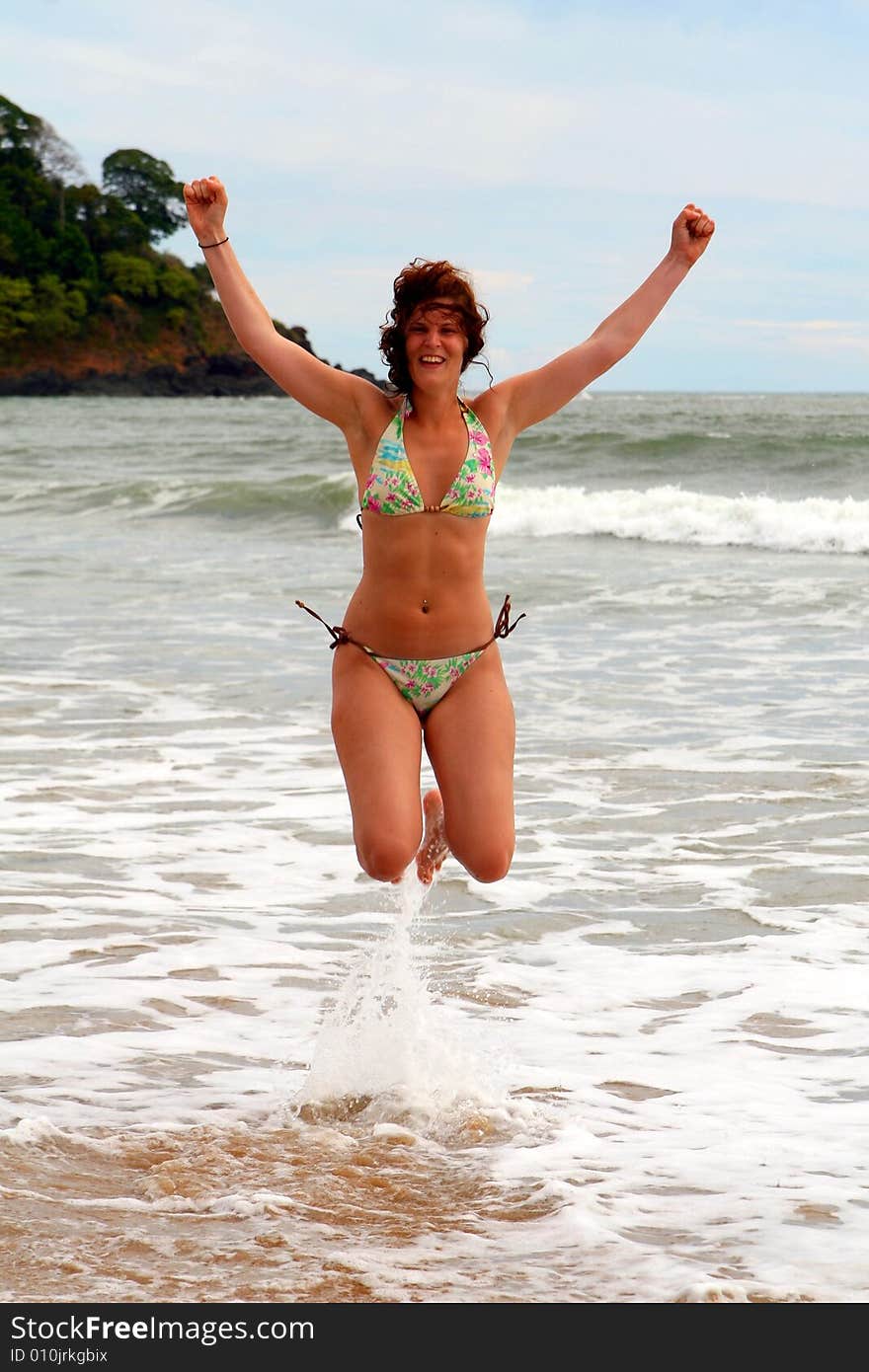 Young woman is jumping at the beach expressing joy and freedom. Ideal vacation / summer shot. Young woman is jumping at the beach expressing joy and freedom. Ideal vacation / summer shot.