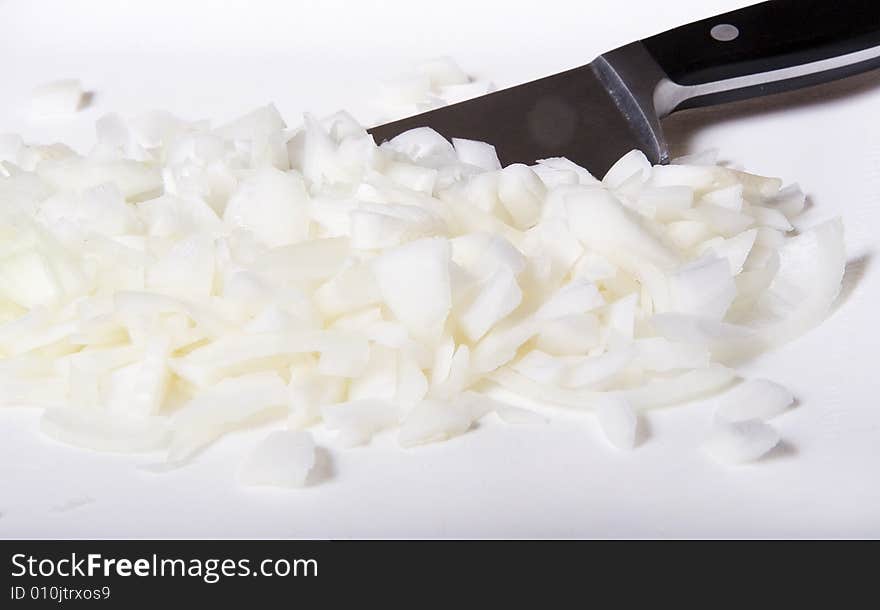 Chopping fresh white onion on a cutting board with knife. Chopping fresh white onion on a cutting board with knife