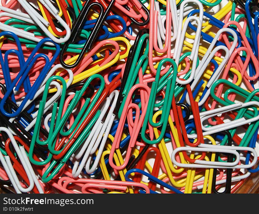 Layer of Coloured Paperclips on a wooden desk. Layer of Coloured Paperclips on a wooden desk