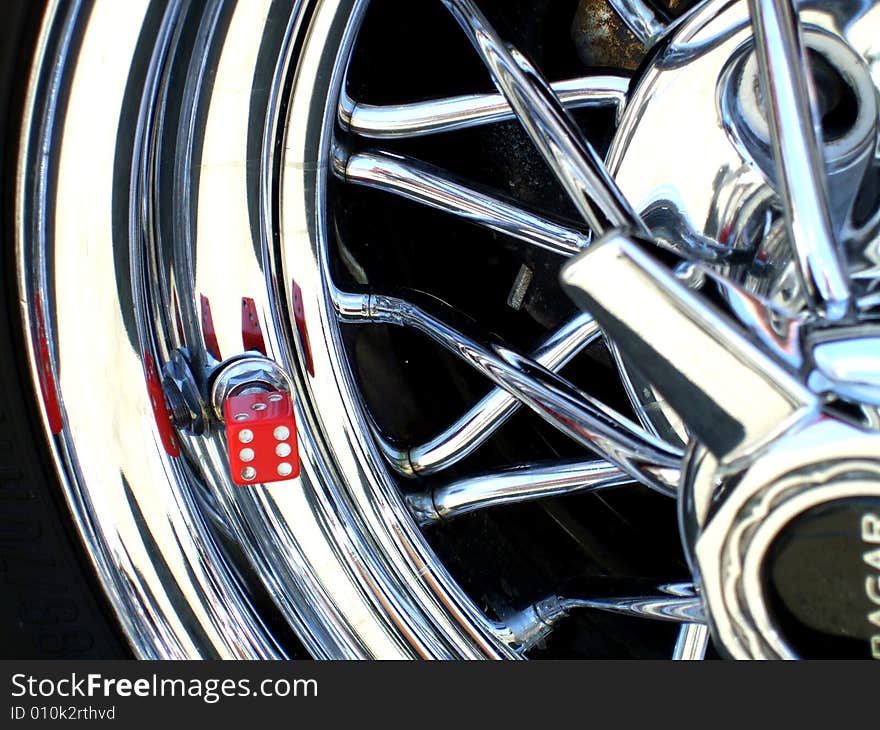 A vintage car wheel with a dice covering the valve stem. A vintage car wheel with a dice covering the valve stem.