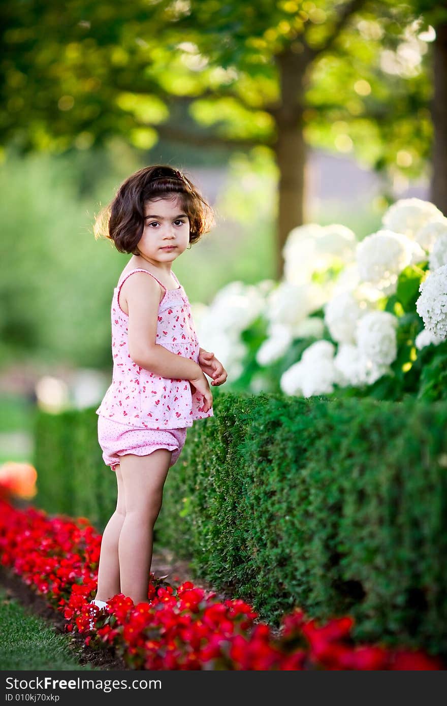 Cute girl in a flower garden looking at flowers. Cute girl in a flower garden looking at flowers