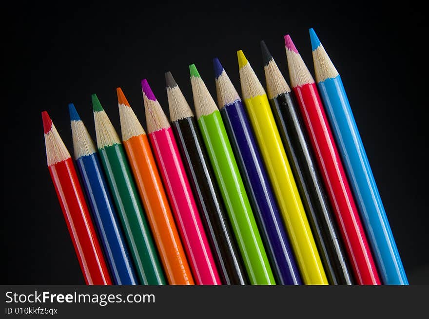 Colored pencil crayons slanted on black background. Colored pencil crayons slanted on black background