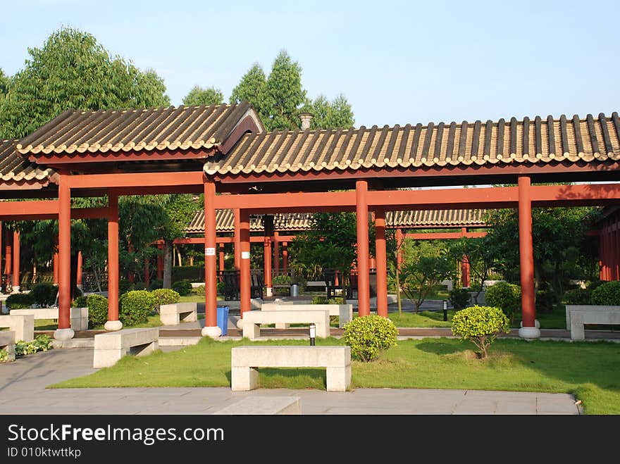 The long roofed corridor with red coloumns in a Chinese ancient garden,stone stools. The long roofed corridor with red coloumns in a Chinese ancient garden,stone stools.