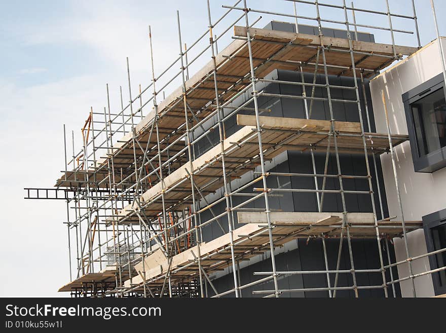 Construction against a blue sky with scaffold covering the building. Construction against a blue sky with scaffold covering the building